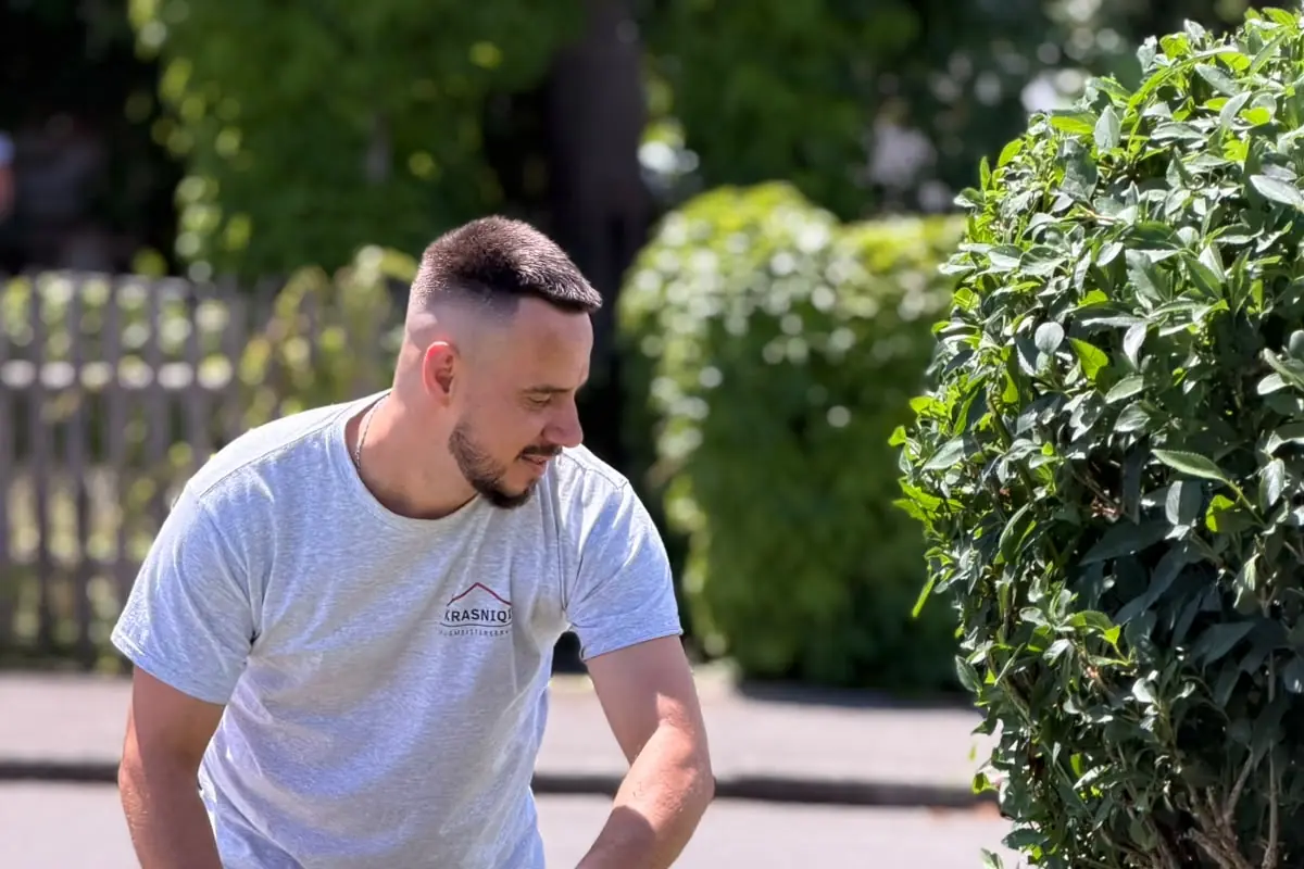 Mitarbeiter schneidet im Frühjahr eine niedrige Hecke in Form