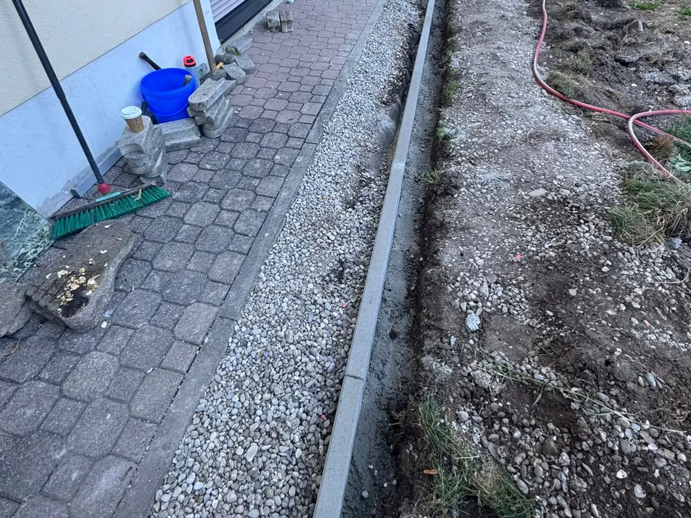 Kiesstreifen mit Entwässerung entlang einer Hauswand