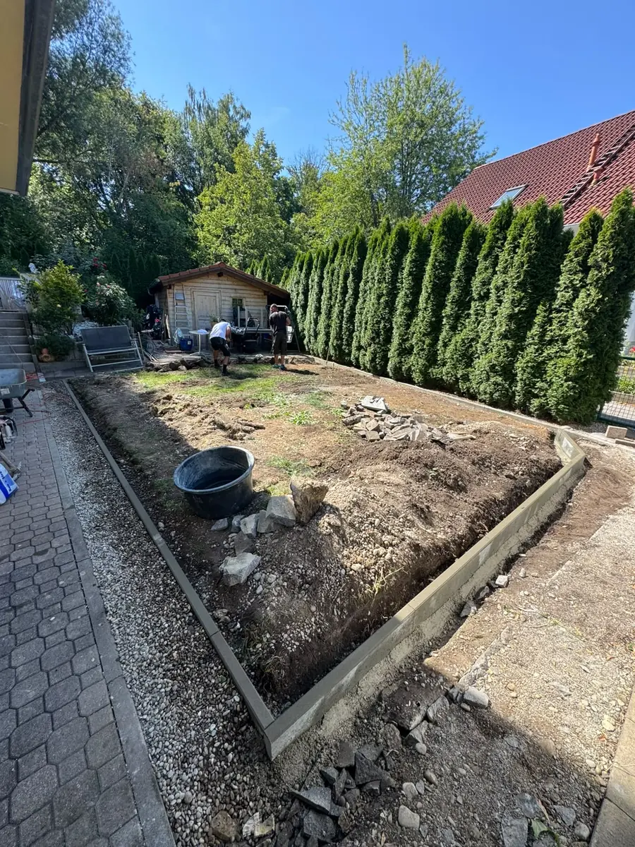 Frisch gesetzte Betoneinfassung entlang eines Beets vor einer Thujahecke
