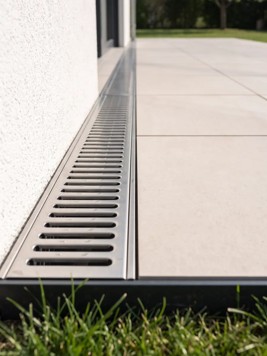 Großformatige Terrassenplatten mit geraden Fugen, Entwässerungsrinne und Rasenkante